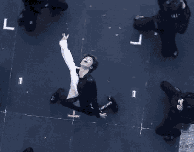 an aerial view of a man in a white shirt and black pants with the number 1 on the floor