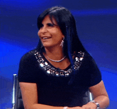 a woman wearing a black top and a silver necklace smiles