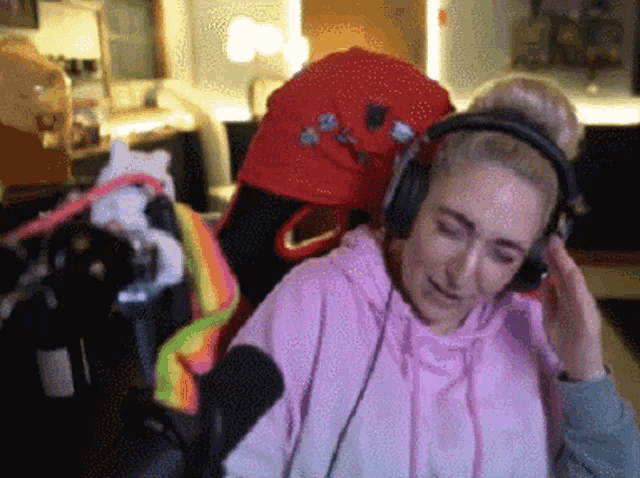 a woman in a pink hoodie is wearing headphones