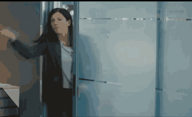a woman in a blue jacket is standing in a doorway