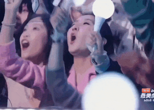 a group of people are holding up their arms in the air while watching a concert ..