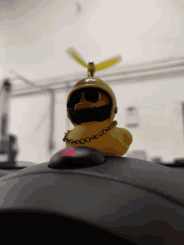 a yellow rubber duck with a chain around its neck and a propeller on its head