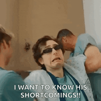 a man wearing sunglasses and a hospital gown is being held by two men .