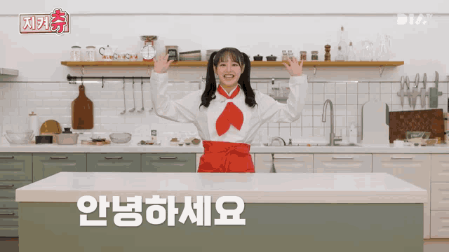 a girl in a red apron is standing in a kitchen with korean writing on the counter top