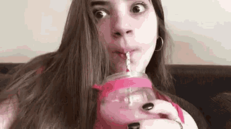 a woman is drinking a smoothie through a straw .