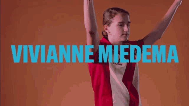 a woman in a red and white adidas shirt holds her arms up in the air