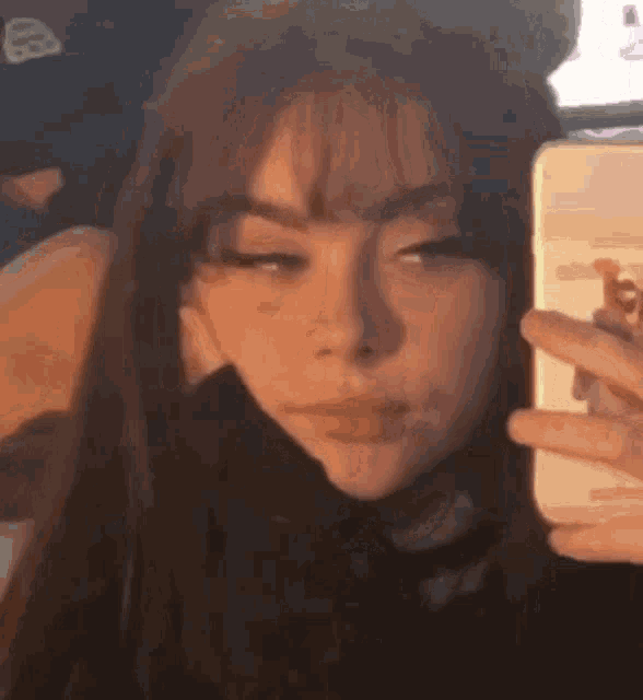 a girl is taking a selfie with her phone in front of a mirror .