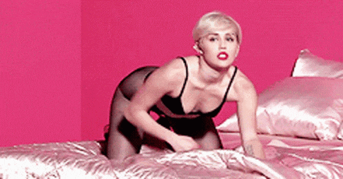 a woman in black lingerie is kneeling on a bed .