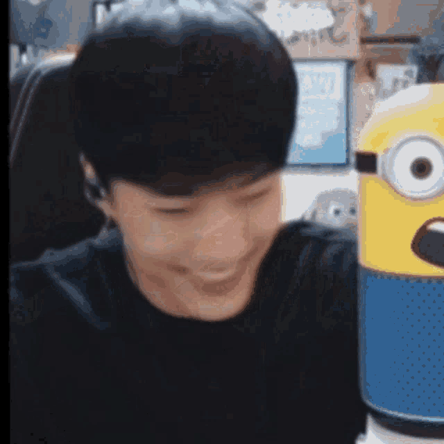 a man in a black shirt is smiling next to a yellow minion