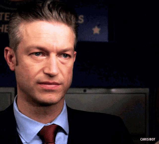 a man in a suit and tie is standing in front of a sign that says us
