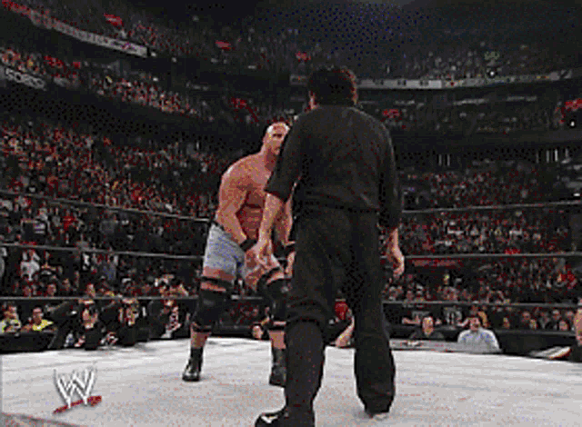a wrestler in a wrestling ring with a referee standing behind him