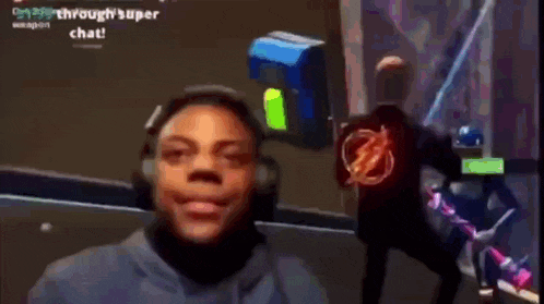 a man wearing headphones and a flash shirt is playing a video game on a computer screen .