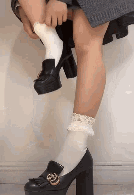 a woman wearing white socks and black shoes with a gold g on the heel