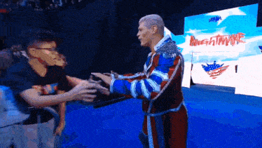 a man in a red white and blue outfit shakes hands with a fan