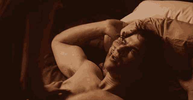 a shirtless man laying on a bed with a tattoo on his arm that says " i love you "