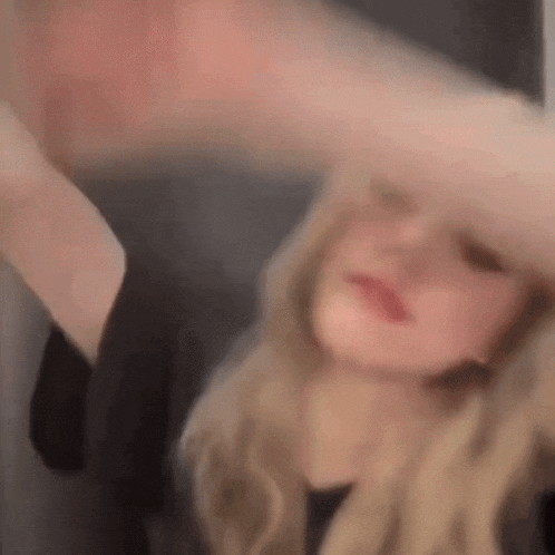 a blurry picture of a woman with long blonde hair covering her face .
