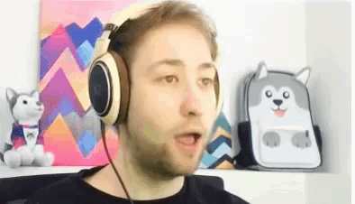 a man wearing headphones is sitting in front of a painting and a backpack .