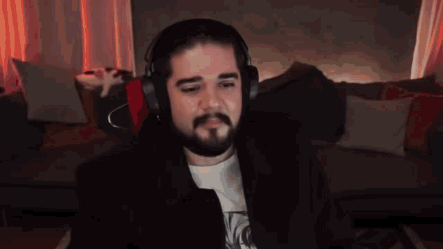 a man wearing headphones is sitting in front of a couch with a cat on it