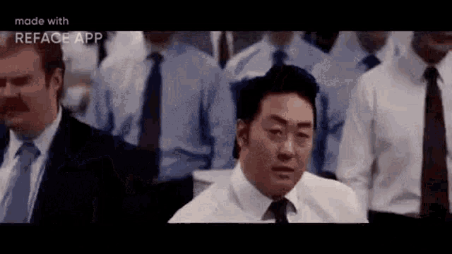 a group of men in suits and ties are sitting in a row .