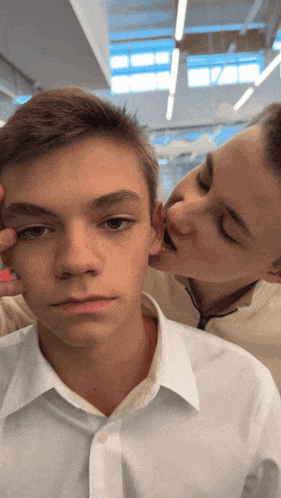 a man kissing another man 's ear while another man looks on