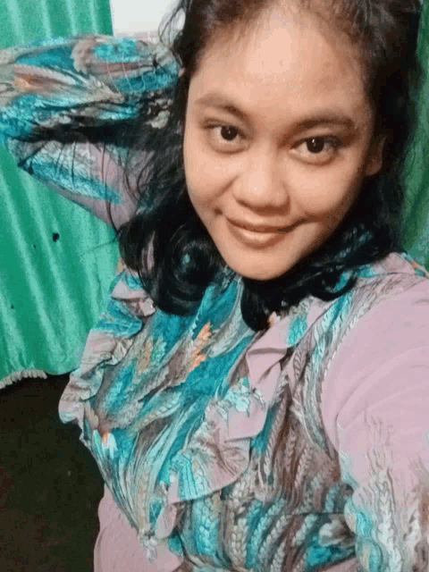 a woman wearing a blue and purple shirt smiles for the camera