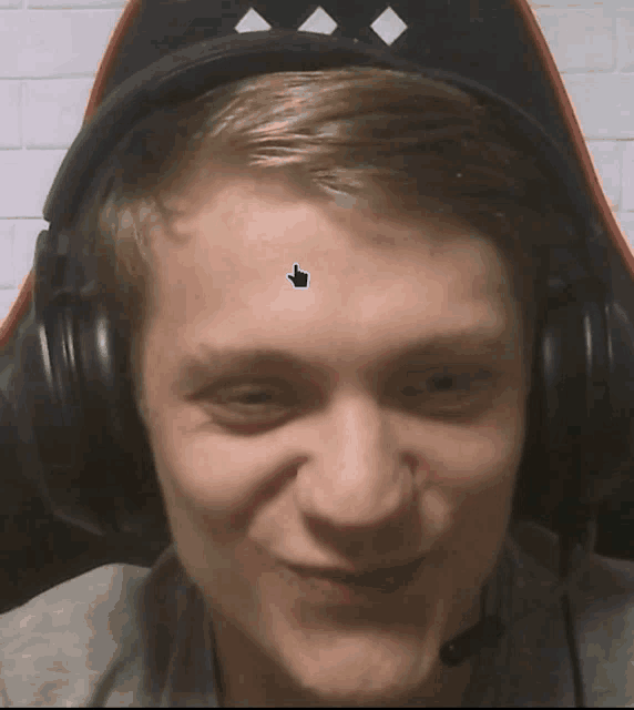 a man wearing headphones has a sticker on his forehead with a hand pointing to it