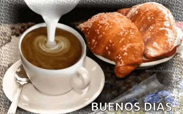 a cup of coffee with croissants and milk being poured into it