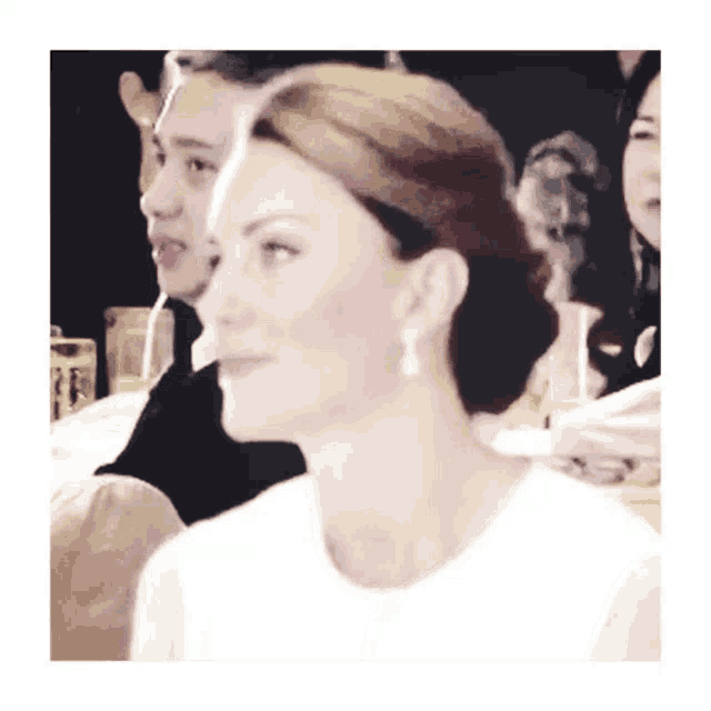 a woman wearing a white shirt and earrings looks at something