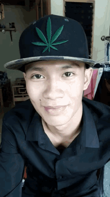 a man wearing a black hat with a green marijuana leaf on it