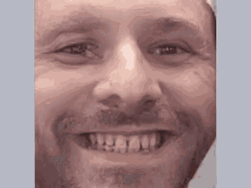 a close up of a man 's face with a beard and a smile .