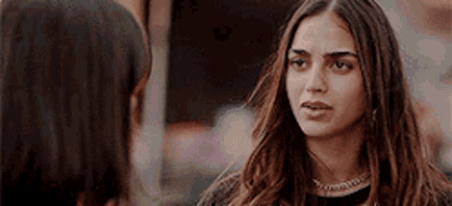 a woman with long hair is talking to another woman while wearing a choker necklace .
