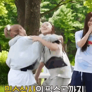 a group of women are standing next to each other in a park and fighting .
