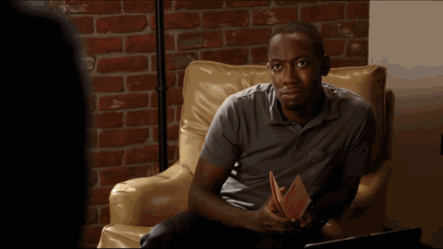 a man sitting in a chair holding a book with the words what written on the bottom