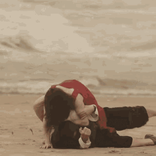 a woman in a red top is laying on the beach with her legs up