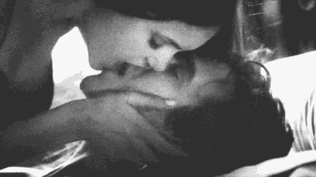 a black and white photo of a woman kissing a man
