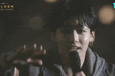 a close up of a person holding a microphone with the words lden on stage behind them