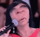 a woman in a red dress is holding a microphone in front of her face and making a funny face .