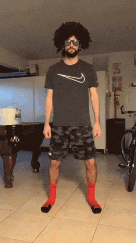 a man wearing a nike shirt and red socks is standing in front of a pool table