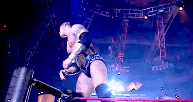 a wrestling match is being held in a ring with a blue background and a few lights .