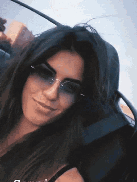 a woman wearing sunglasses sits in a car
