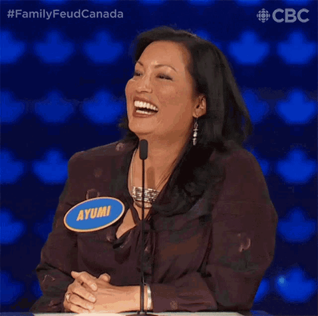 a woman with a name tag that says ayumi laughs in front of a microphone