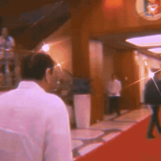 a man in a white shirt is walking down a red carpeted hallway
