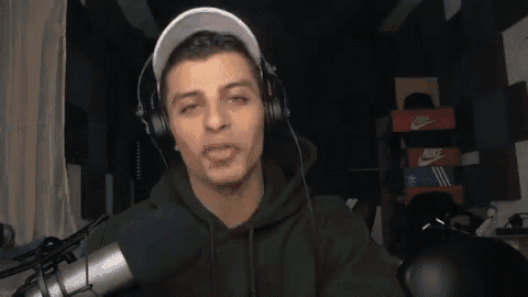 a young man wearing headphones and a baseball cap is talking into a microphone .