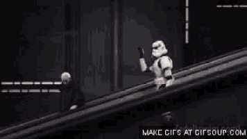 a group of stormtroopers are standing on top of an escalator and giving the middle finger .