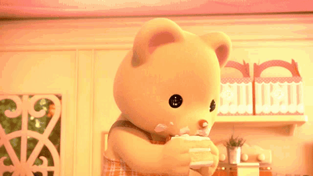 a teddy bear is holding a piece of cake with icing on it