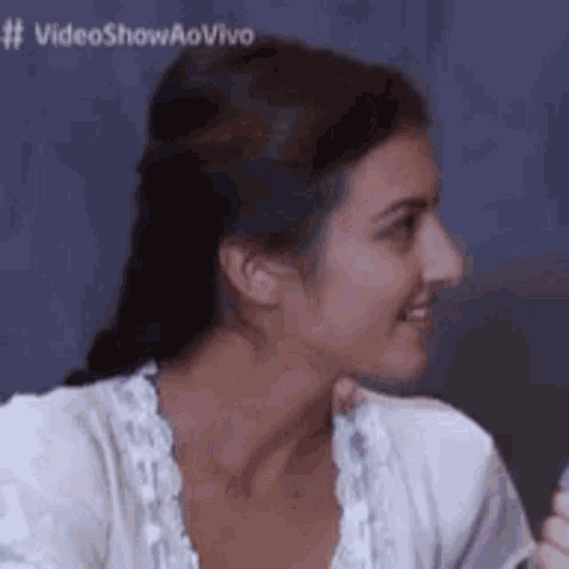 a woman is smiling and looking at the camera while wearing a white top .
