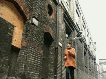 a woman in an orange sweater walks down a brick street