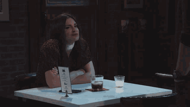 a woman sits at a table with a sign that says ' a ' on it