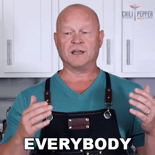 a man wearing an apron says everybody in front of a chili pepper sign