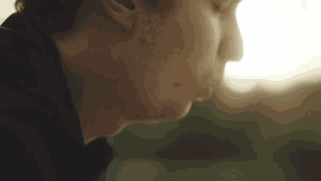 a close up of a man 's face with the sun shining through the window in the background .